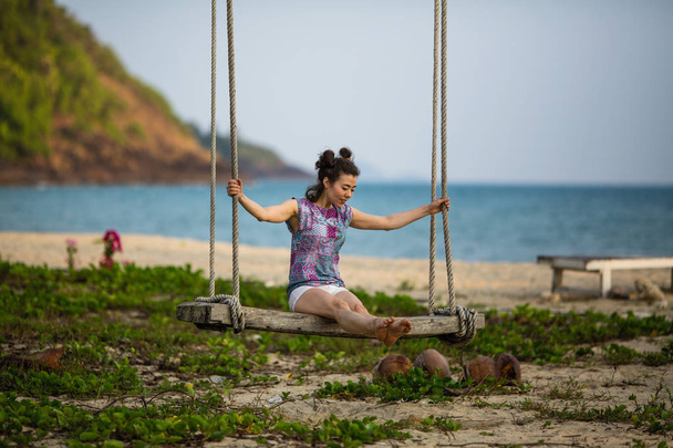 Asian woman swinging on a swing on a tropical beach. - Фото, зображення