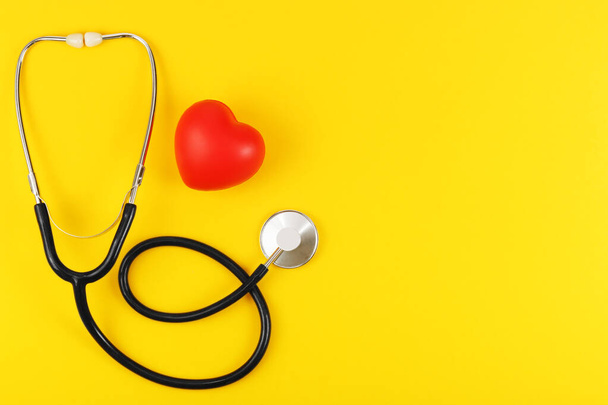Red heart and stethoscope on a yellow background. - Fotografie, Obrázek
