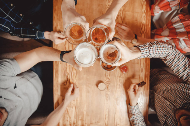 Пласка фотографія. Чоловіки друзі клінтують келихи пива в барі. Вид зверху
 - Фото, зображення