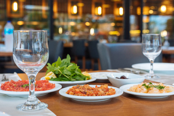 Sisä- tai ulkotiloissa kreikkalainen tai turkkilainen ravintola illallinen tai lounaspöytä salaateilla ja alkupaloilla. Päivällispöydän asetukset
 - Valokuva, kuva