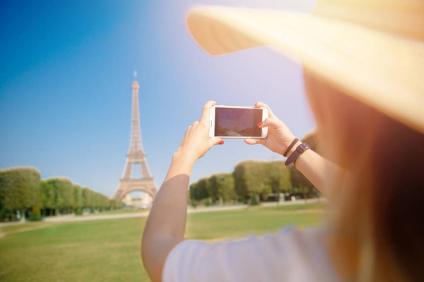 Travel blogger młoda kobieta w kapeluszu bierze zdjęcie wieży Eiffla na telefon w Paryżu, Francja - Zdjęcie, obraz