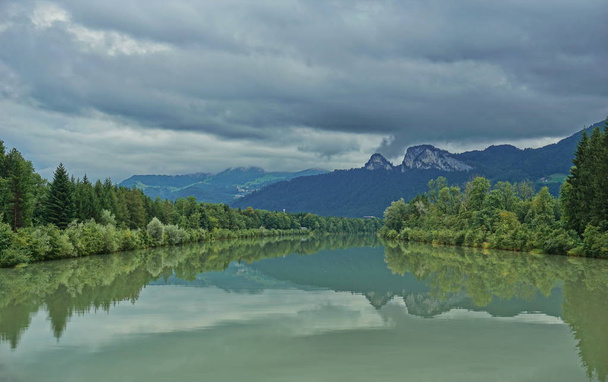 Taustalla vuoria heijastava joki
 - Valokuva, kuva