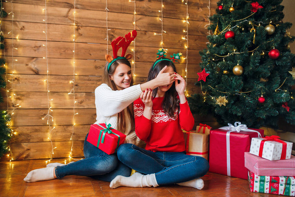 happy girl friends exchanging presents in Christmas decorated living room - Foto, Imagem