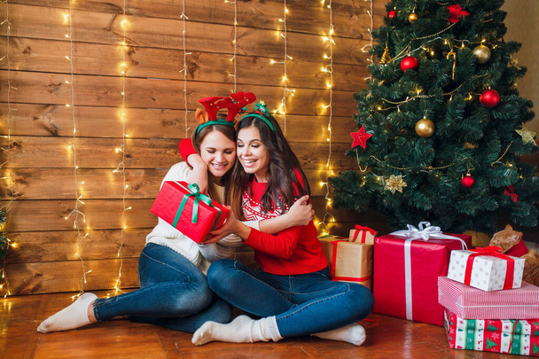 Two beautiful young women giving a christmas present each other - Fotografie, Obrázek