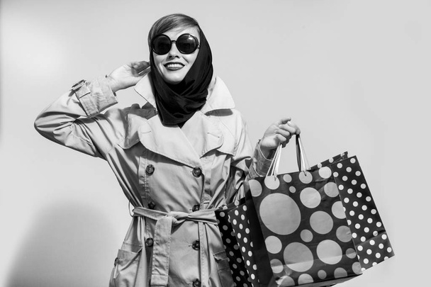 Happy shopping woman with shopping bags wearing trendy coat and scarf - Photo, image
