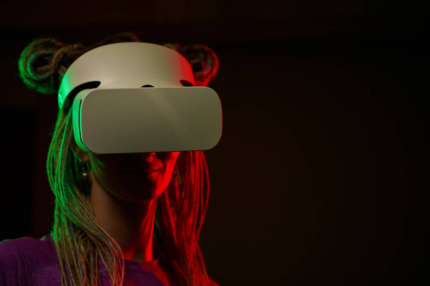 La femme utilise un casque de réalité virtuelle. Portrait studio lumière néon. - Photo, image