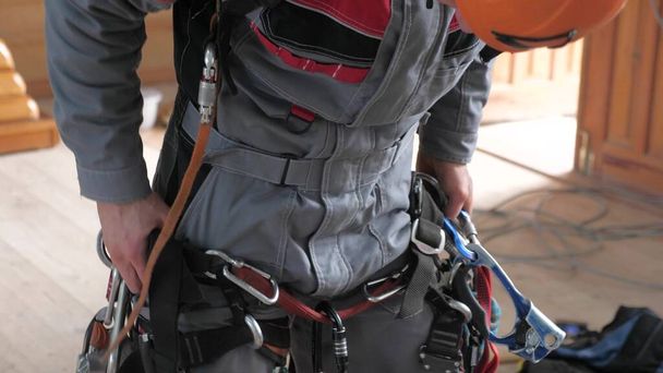 alpinista industrial coloca em equipamentos para trabalho de alta altitude. nos mosquetões de cinto de alpinista
. - Foto, Imagem