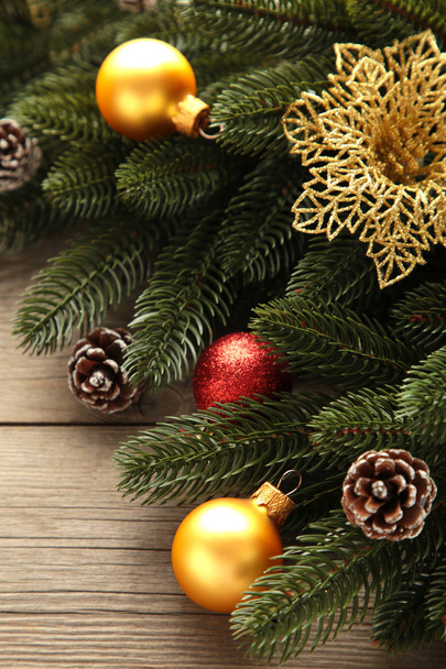 Christmas decoration. Fir-tree branch with red and gold balls on grey background - Zdjęcie, obraz