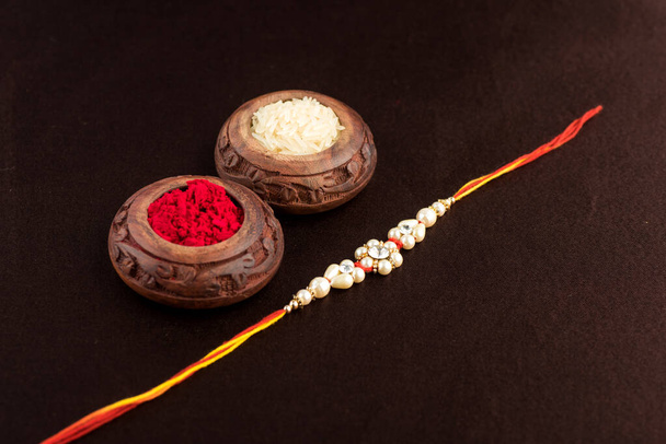 Raksha Bandhan background with an elegant Rakhi, Rice Grains and Kumkum. A traditional Indian wrist band which is a symbol of love between Brothers and Sisters. - Zdjęcie, obraz