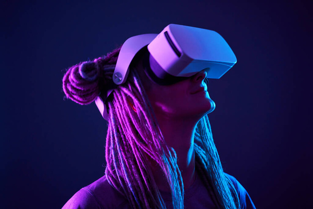 A nő virtuális valóság headsetet használ. Neon light stúdió portré. - Fotó, kép