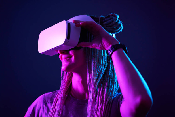 Woman is using virtual reality headset. Neon light studio portrait. - Φωτογραφία, εικόνα