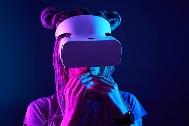 Woman is using virtual reality headset. Neon light studio portrait. - Photo, Image