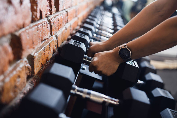 Close-up girl start watch grabs heavy dumbbell in gym with his hand. Concept lifting, fitness - Foto, Imagem