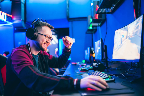 Joueur professionnel jouant tournois jeux vidéo en ligne ordinateur avec écouteurs, rouge et bleu - Photo, image