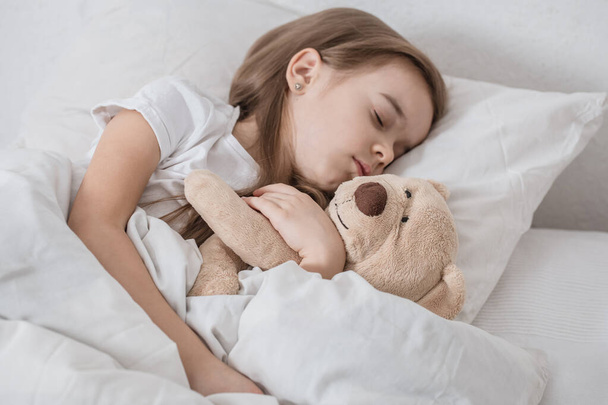 Cute little girl in bed with soft toy. - Foto, imagen