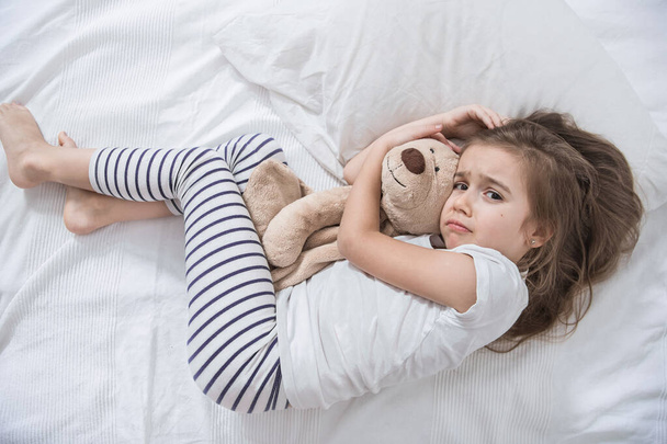 Schattig klein meisje in bed met zacht speelgoed. - Foto, afbeelding