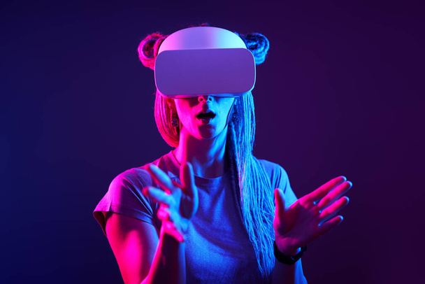 Woman is using virtual reality headset. Neon light studio portrait. - Photo, Image