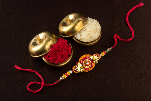 Raksha Bandhan pozadí s elegantním Rakhi, rýže zrna a Kumkum. Tradiční indický náramek, který je symbolem lásky mezi bratry a sestrami. - Fotografie, Obrázek