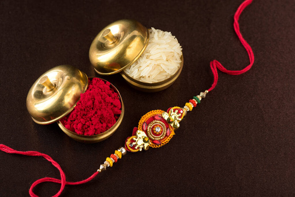Raksha Bandhan background with an elegant Rakhi, Rice Grains and Kumkum. A traditional Indian wrist band which is a symbol of love between Brothers and Sisters. - Fotoğraf, Görsel