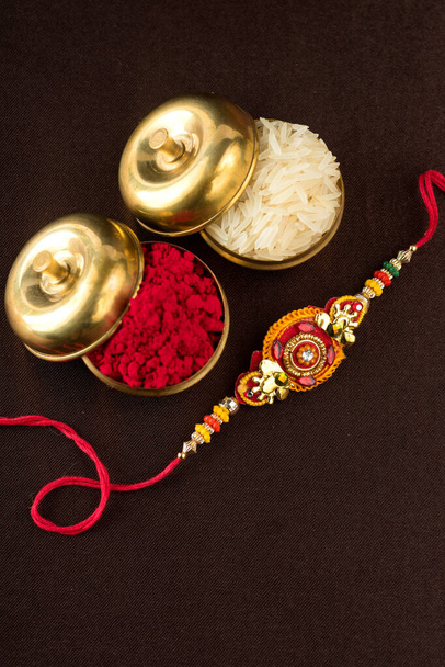 Raksha Bandhan background with an elegant Rakhi, Rice Grains and Kumkum. A traditional Indian wrist band which is a symbol of love between Brothers and Sisters. - Photo, Image