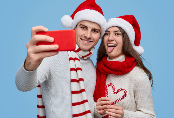 Funny couple making selfie with candy canes - Foto, Imagem
