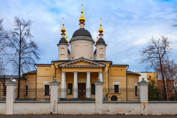 Orthodox church of yellow color with golden domes and white columns against a cloudy sky - Foto, immagini