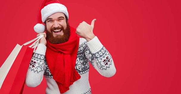 Cheerful guy pointing aside during Christmas shopping - 写真・画像