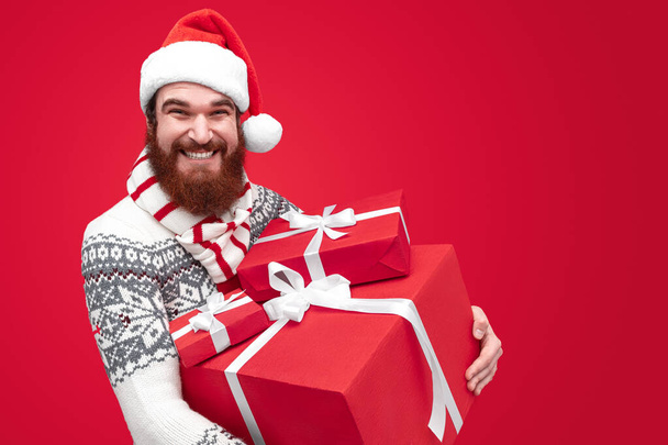 Bearded man in Santa hat carrying presents - Foto, afbeelding