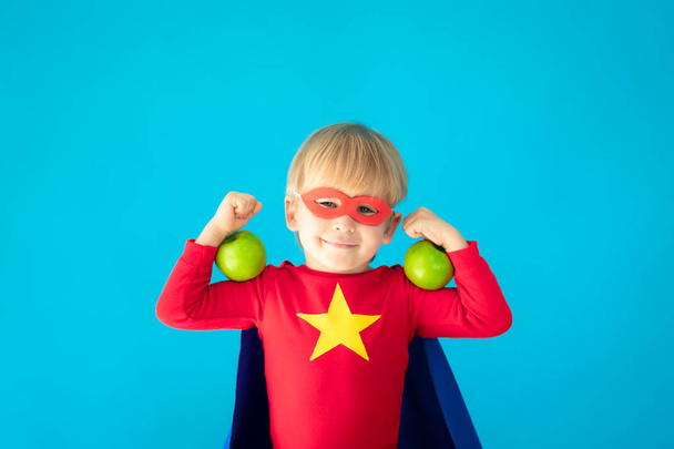 Superhero child holding apple - Φωτογραφία, εικόνα