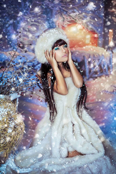 Attractive Christmas photo of a model girl who is photographed on the background of Christmas decorations in artificial snow - Foto, immagini