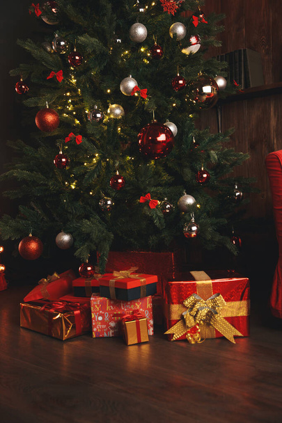 Beautiful Christmas gift boxes on floor near fir tree in room - Fotó, kép