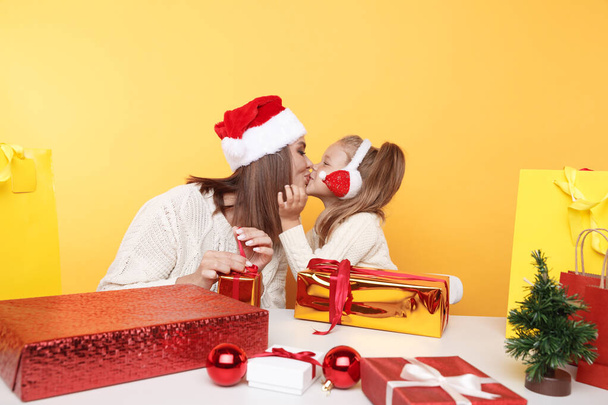 Madre con figlia che siede insieme alla scrivania di Natale e si bacia
. - Foto, immagini