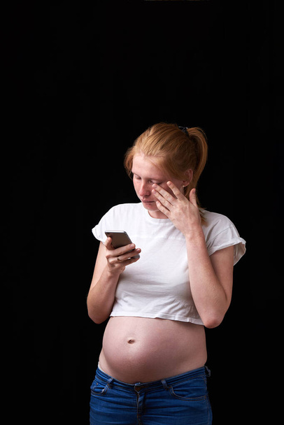 pregnancy, motherhood, technology, people and expectation concept - sad pregnant woman calling on smartphone at home. upset pregnant woman with phone in her hands. technology and pregnancy - Фото, изображение