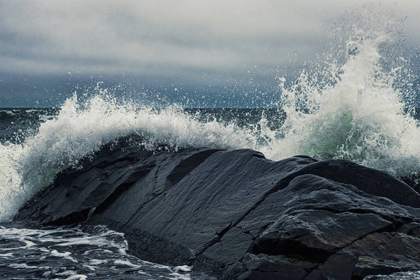 Хвилі, що ламаються на березі чорних скель
 - Фото, зображення