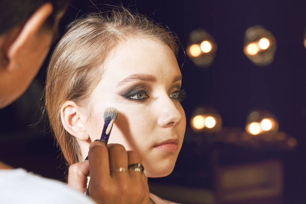 Maquillaje artista aplicando base tonal líquida en la cara de la mujer - Foto, imagen