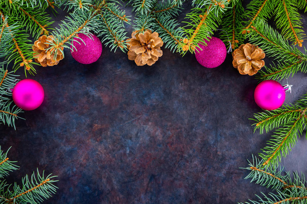 クリスマスの飾りモミの枝、松のコーンとピンクのボールとクリスマスの装飾的な背景の境界。暗い背景にクリスマススプルースの枝。コピースペース平敷 - 写真・画像