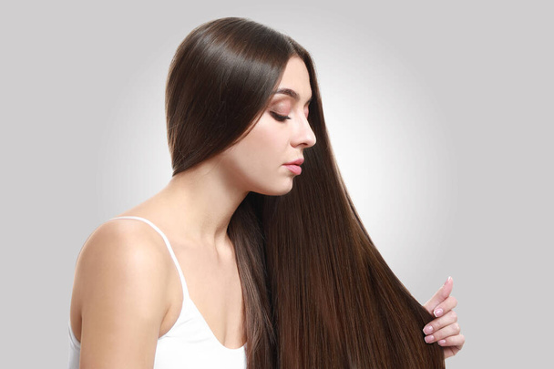 Gyönyörű nő egészséges hosszú haj fény háttér - Fotó, kép