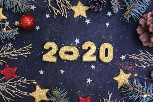 Año Nuevo piso laico 2020. Sobre un fondo oscuro, dorados números brillantes 2020 en brillo, ramas de abeto, juguetes de Navidad y una guirnalda
. - Foto, Imagen