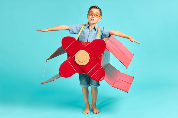 Funny little boy in casual clothes in cardboard plane - Fotoğraf, Görsel