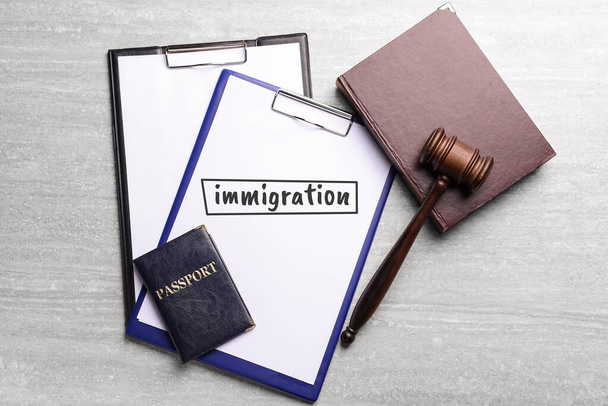 Młot sędziowski, schowki, książka, paszport i schowek z tekstem Imigracja na stole - Zdjęcie, obraz