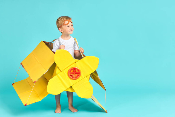 Uroczy chłopiec 5 lat w tekturowym żółtym samolocie - Zdjęcie, obraz