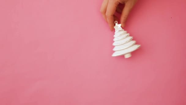 einfach minimales Design weibliche Hand hält Weihnachtsschmuck Tanne Baum isoliert auf rosa Pastell bunte trendige Hintergrund - Filmmaterial, Video