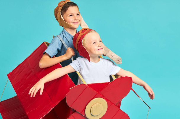 Cute dreamer boys flying in cardboard airplane. Childhood. - Фото, зображення