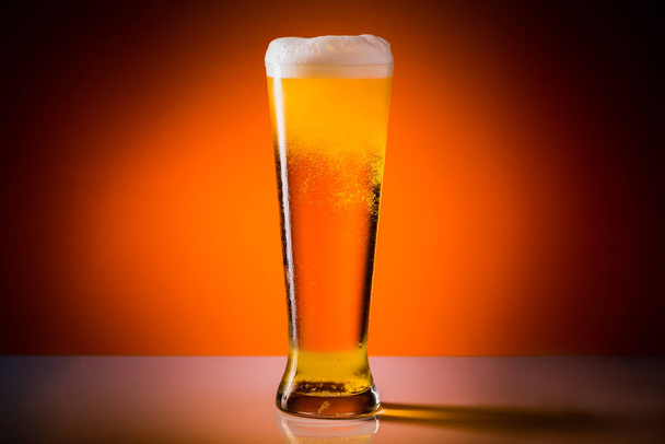 Sklenice na pivo s kapkami na oranžovém pozadí. Koncept alkoholu. Kopírovat prostor - Fotografie, Obrázek