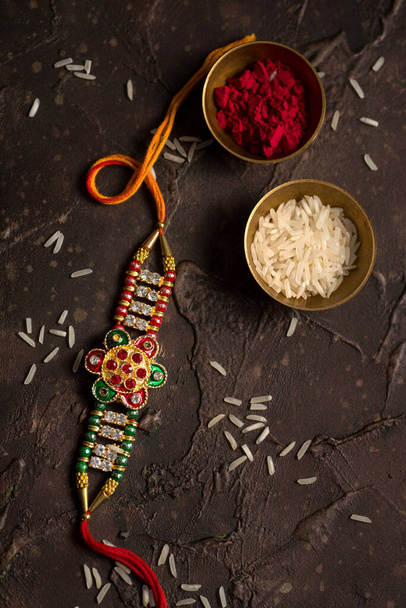 Raksha Bandhan background with an elegant Rakhi, Rice Grains and Kumkum. A traditional Indian wrist band which is a symbol of love between Brothers and Sisters. - Photo, Image
