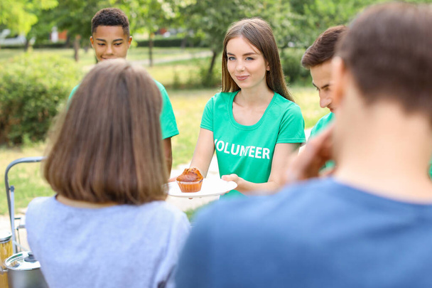 Jóvenes voluntarios dando comida a los pobres al aire libre
 - Foto, Imagen