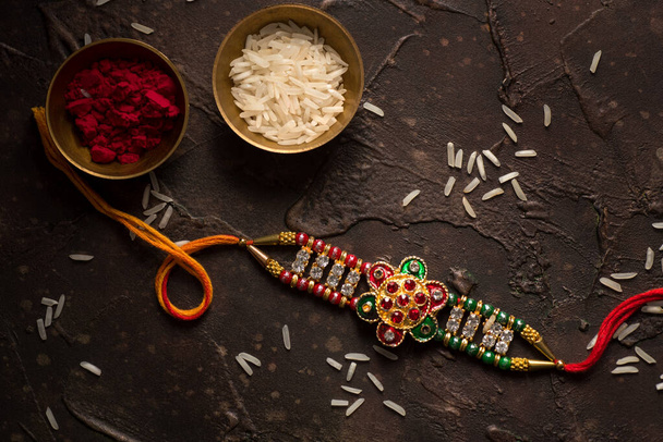 Raksha Bandhan background with an elegant Rakhi, Rice Grains and Kumkum. A traditional Indian wrist band which is a symbol of love between Brothers and Sisters. - Zdjęcie, obraz