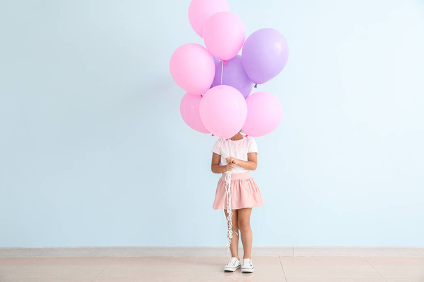 Little girl with balloons near color wall - Fotó, kép