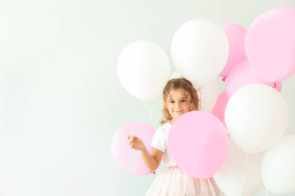 Little girl with balloons on light background - Foto, Imagem