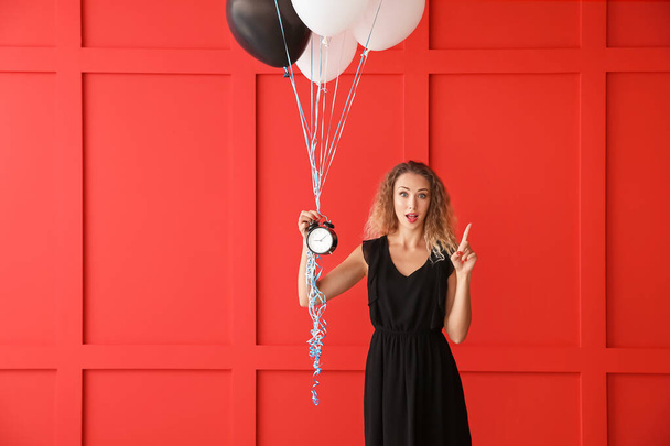Beautiful young woman with balloons and clock on color background - Foto, immagini